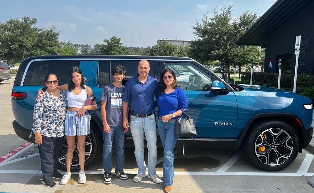A group standing beside a blue Rivian R1S