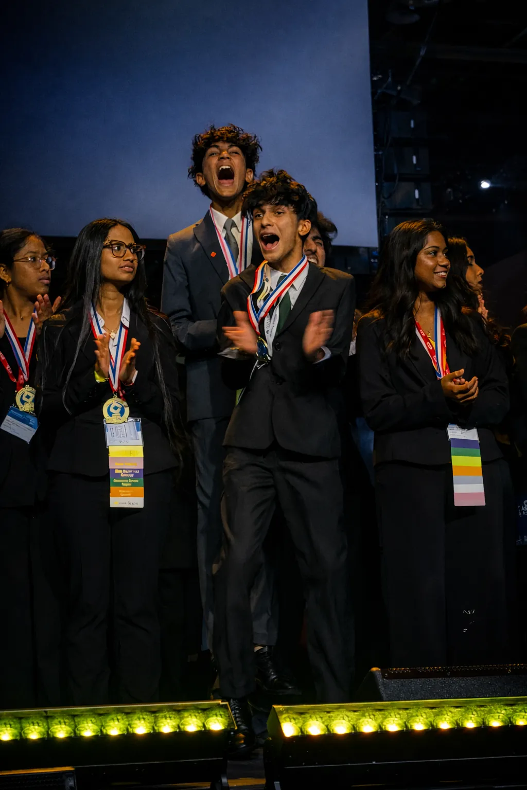 Devansh and teammates celebrating on a DECA stage