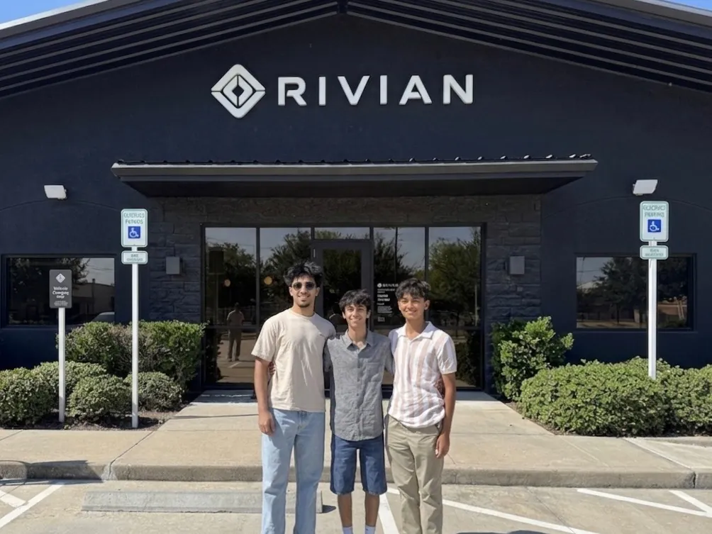 Devansh and two teammates standing outside a Rivian building
