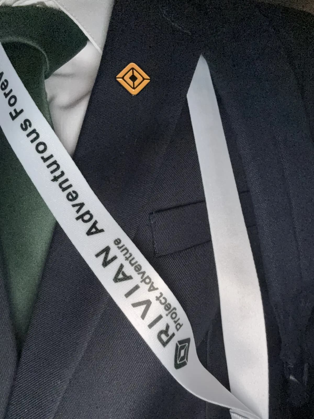 A Rivian Project Adventure lanyard and pin on a blazer
