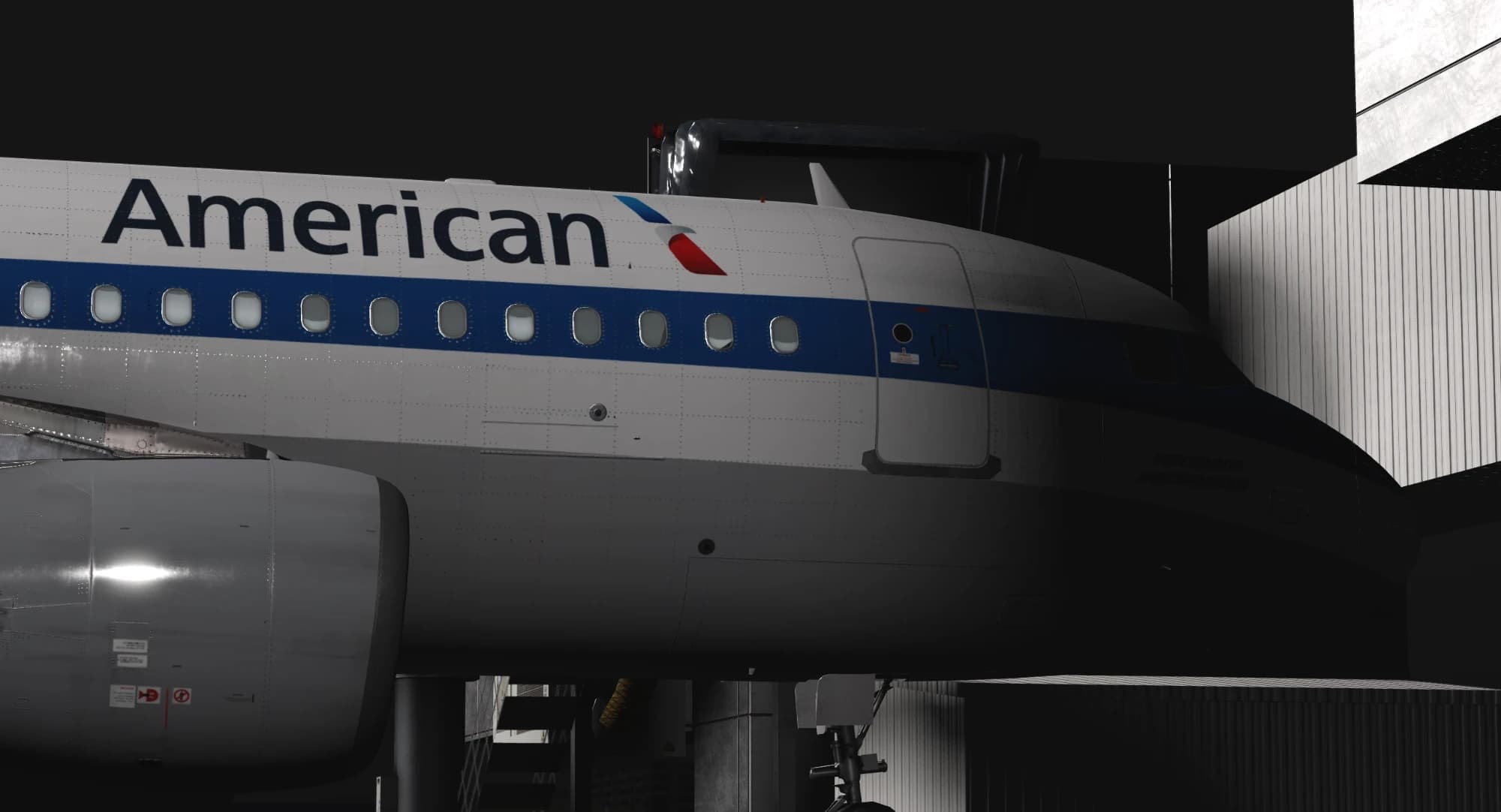 An American Airlines jet with a blue cheatline in a dark hangar